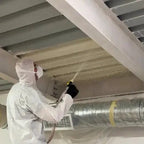 video of worker in a protective suit and mask applying Honeyfoam spray foam insulation